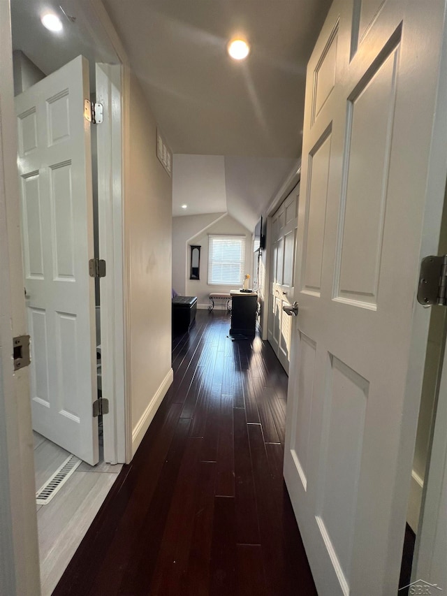 corridor with vaulted ceiling and dark hardwood / wood-style floors