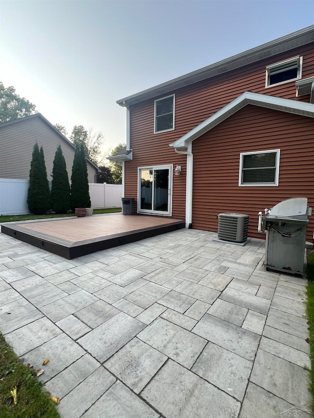 rear view of property featuring a deck, cooling unit, and a patio area