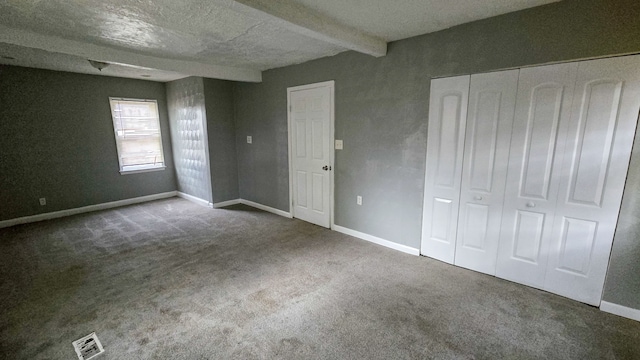 unfurnished bedroom with carpet, beam ceiling, and a closet