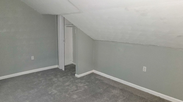 bonus room featuring vaulted ceiling and dark carpet