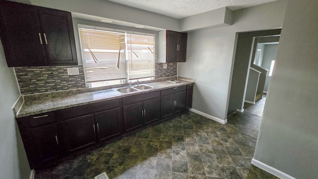 kitchen featuring dark brown cabinetry, decorative backsplash, and sink