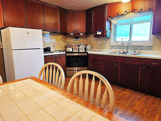 kitchen with electric range, sink, white fridge, decorative backsplash, and hardwood / wood-style flooring