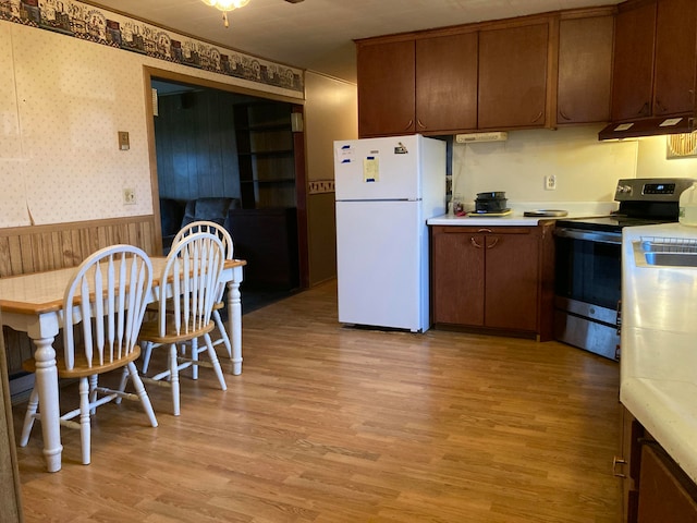 kitchen featuring stainless steel electric stove, white fridge, and light hardwood / wood-style floors