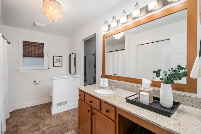 bathroom with vanity, an inviting chandelier, and toilet