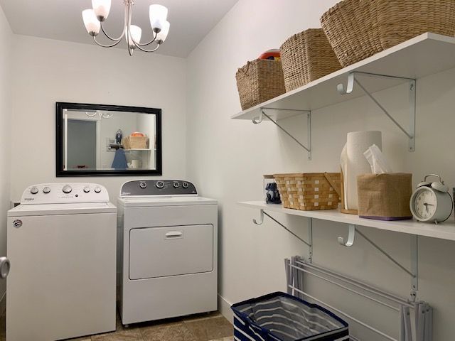 washroom featuring washing machine and clothes dryer and an inviting chandelier