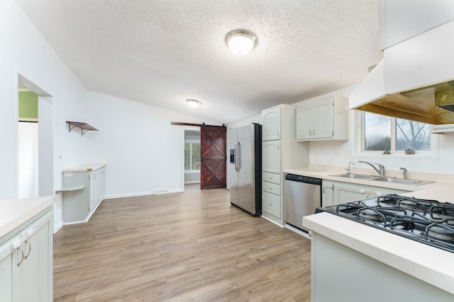 kitchen with a barn door, white cabinets, a healthy amount of sunlight, and appliances with stainless steel finishes