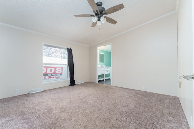 carpeted spare room featuring ceiling fan, vaulted ceiling, and ornamental molding