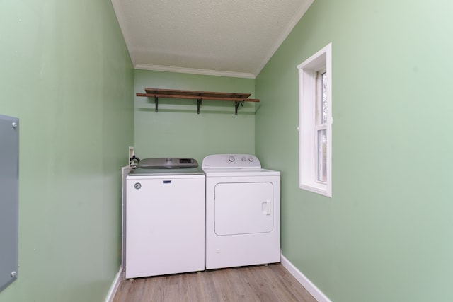 clothes washing area featuring a textured ceiling, separate washer and dryer, light hardwood / wood-style flooring, and crown molding