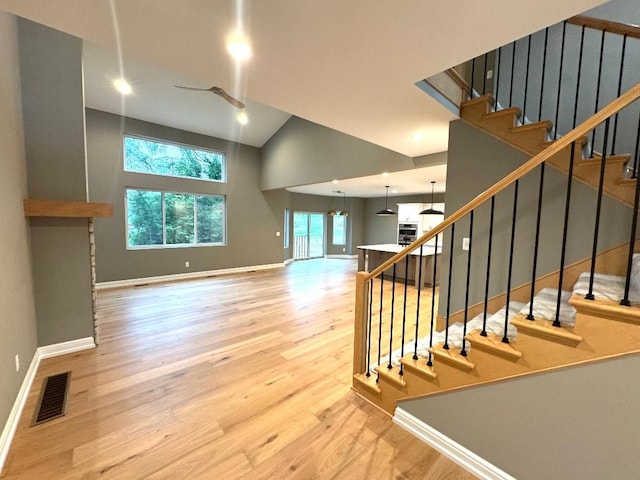 stairway featuring hardwood / wood-style flooring and high vaulted ceiling