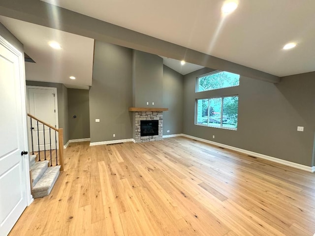 unfurnished living room with a fireplace, light hardwood / wood-style floors, and vaulted ceiling with beams