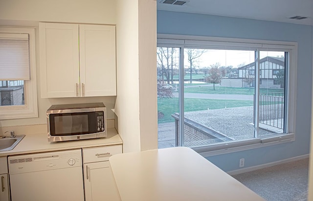 kitchen featuring white dishwasher, sink, and white cabinetry