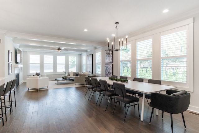 dining space with dark hardwood / wood-style flooring, a healthy amount of sunlight, ceiling fan with notable chandelier, and ornamental molding