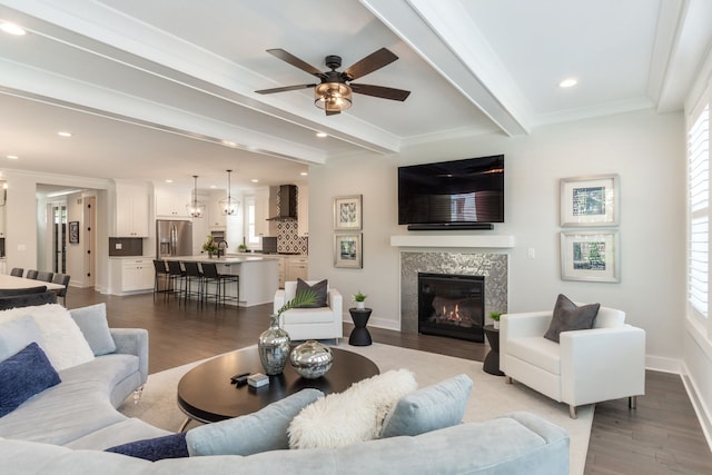 living room featuring ceiling fan, plenty of natural light, beamed ceiling, and light hardwood / wood-style flooring