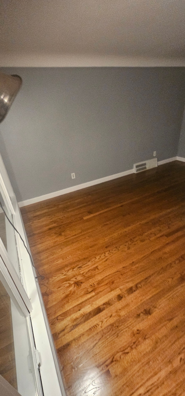 unfurnished room featuring hardwood / wood-style flooring and lofted ceiling