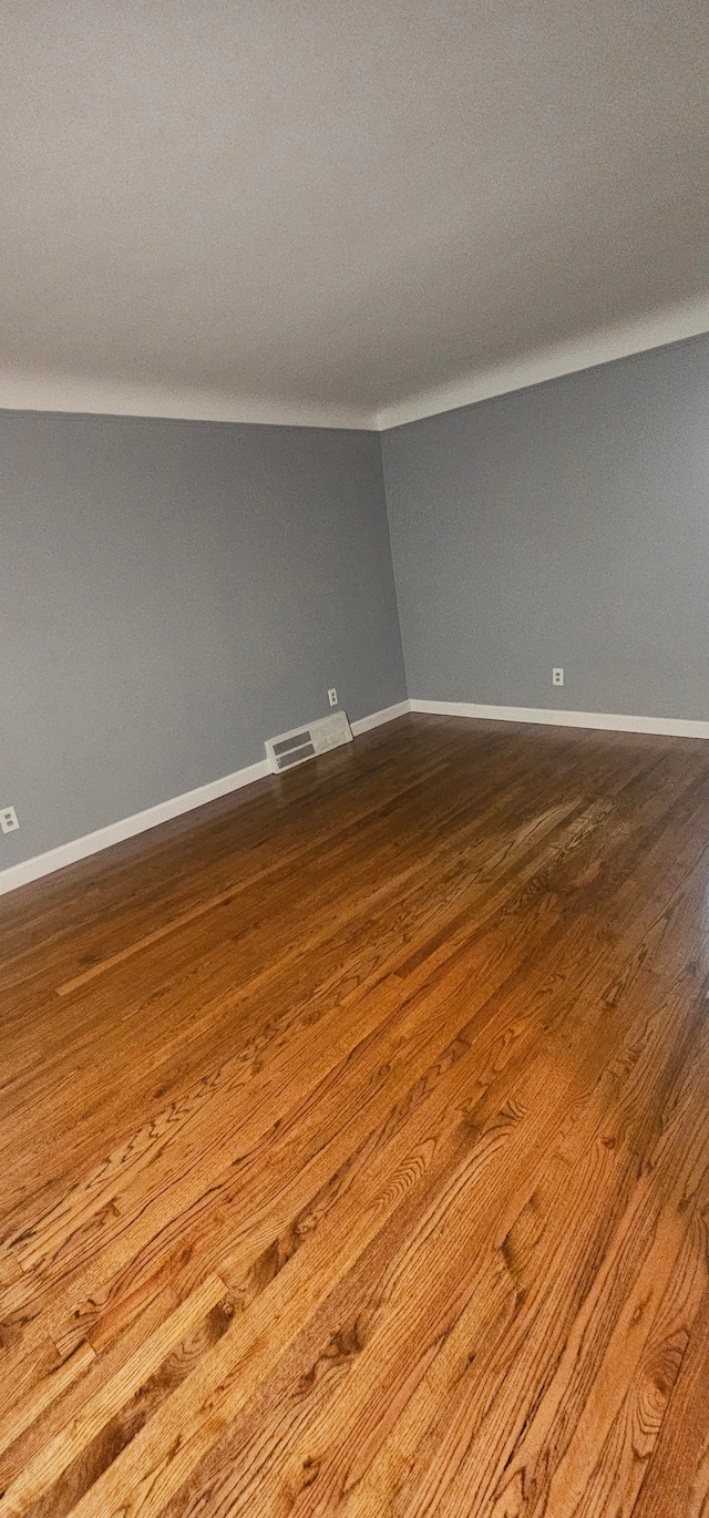 spare room with hardwood / wood-style flooring and vaulted ceiling