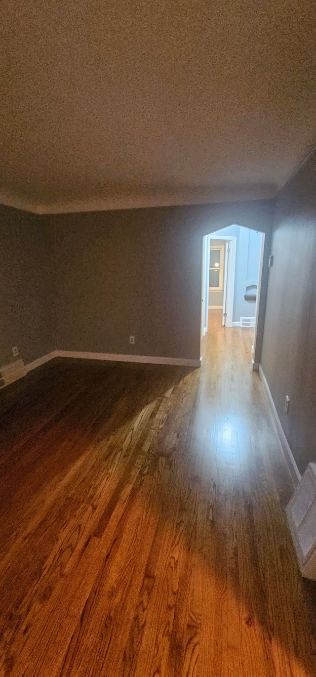 empty room with hardwood / wood-style floors and a textured ceiling