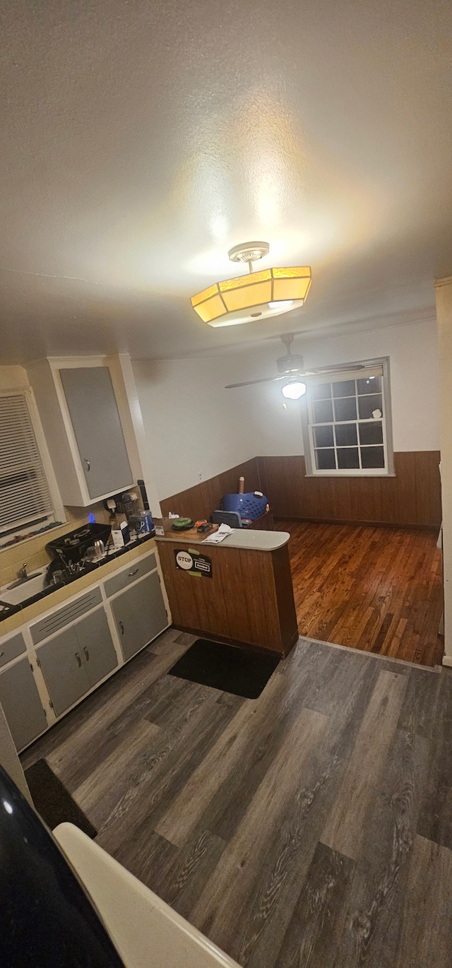 kitchen featuring kitchen peninsula, a textured ceiling, dark hardwood / wood-style floors, and wood walls