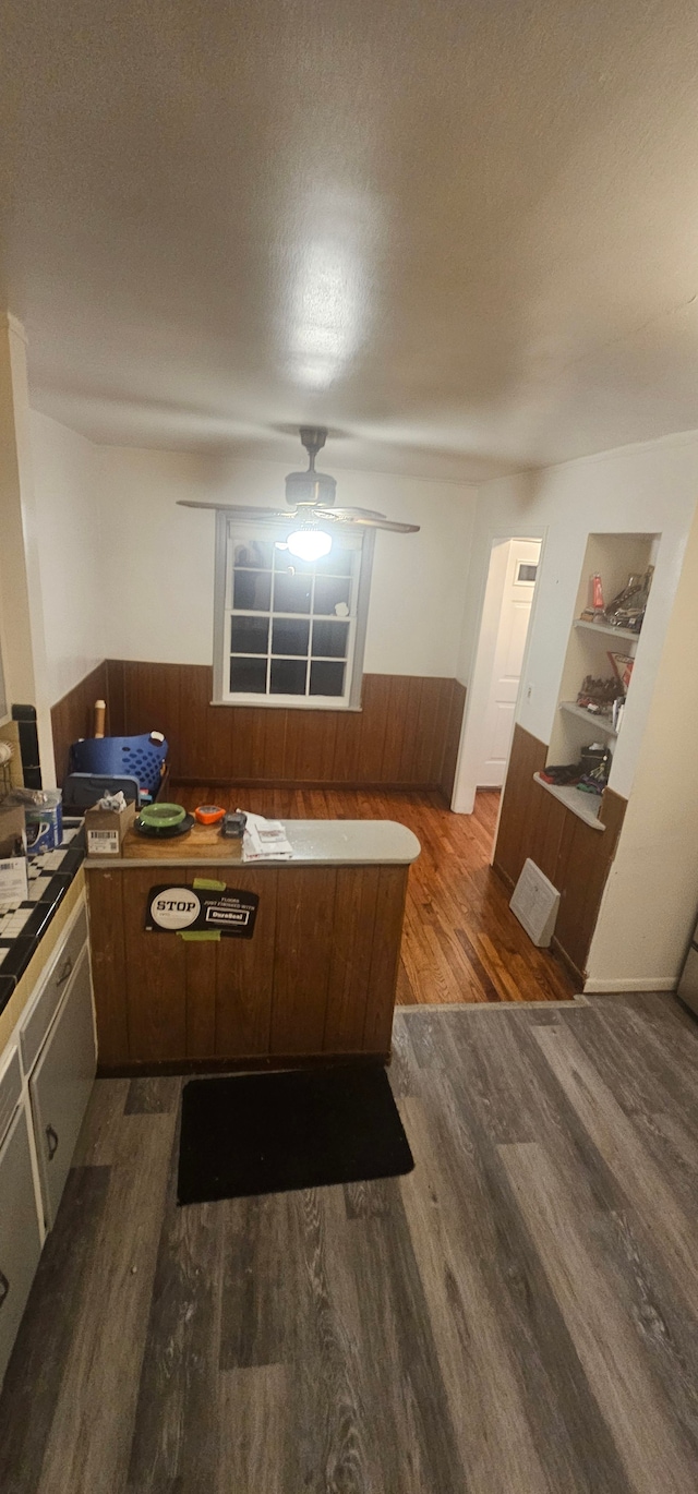 kitchen with dark hardwood / wood-style floors, wood walls, a textured ceiling, and built in shelves