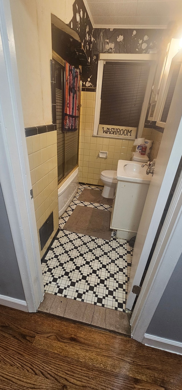 full bathroom with shower / bath combination with glass door, wood-type flooring, toilet, and tile walls