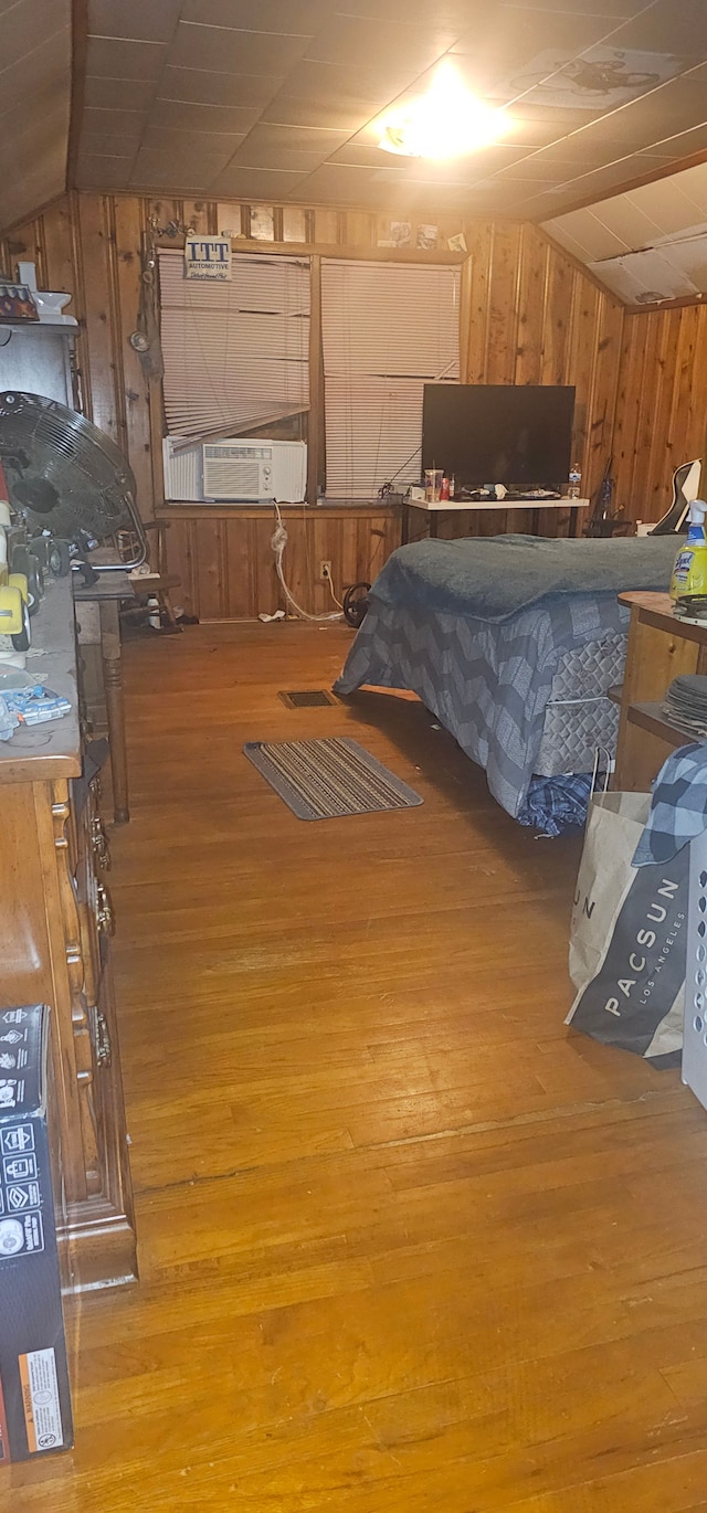 bedroom with light hardwood / wood-style floors, vaulted ceiling, and wooden walls