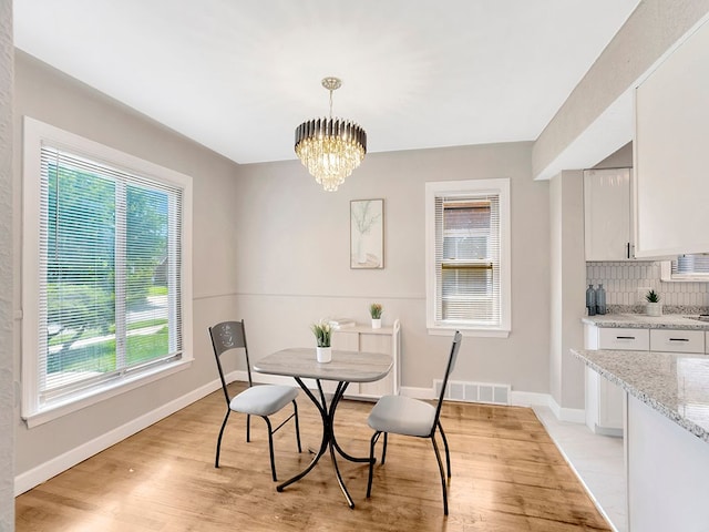 dining space featuring light hardwood / wood-style floors and a notable chandelier