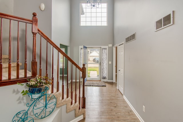 foyer entrance featuring a towering ceiling and light wood-type flooring