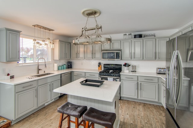 kitchen featuring sink, light hardwood / wood-style flooring, a kitchen island, and appliances with stainless steel finishes