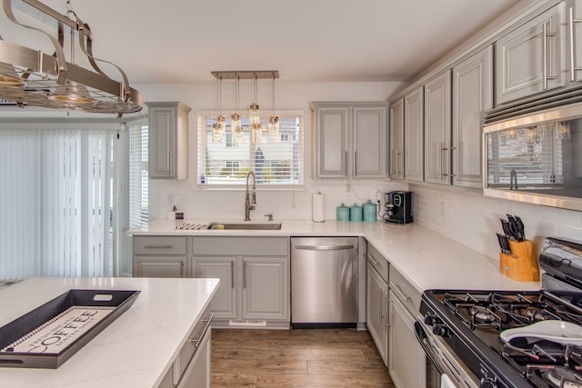 kitchen featuring decorative backsplash, appliances with stainless steel finishes, sink, pendant lighting, and dark hardwood / wood-style floors