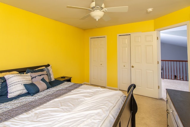 bedroom with light carpet, two closets, and ceiling fan