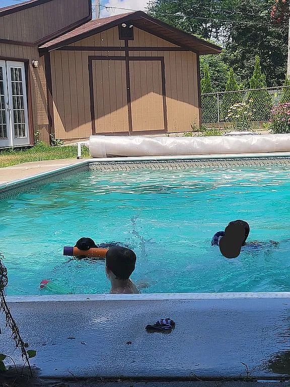 view of swimming pool featuring french doors and a storage shed