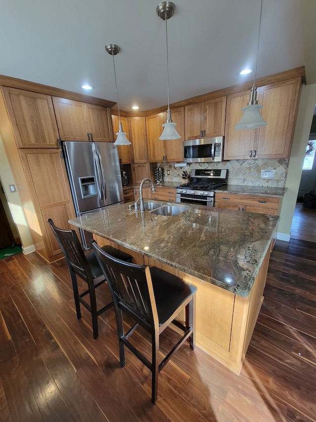 kitchen with appliances with stainless steel finishes, backsplash, dark wood-type flooring, sink, and pendant lighting