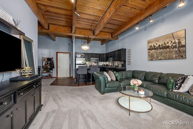 carpeted living room featuring beamed ceiling, track lighting, and wood ceiling