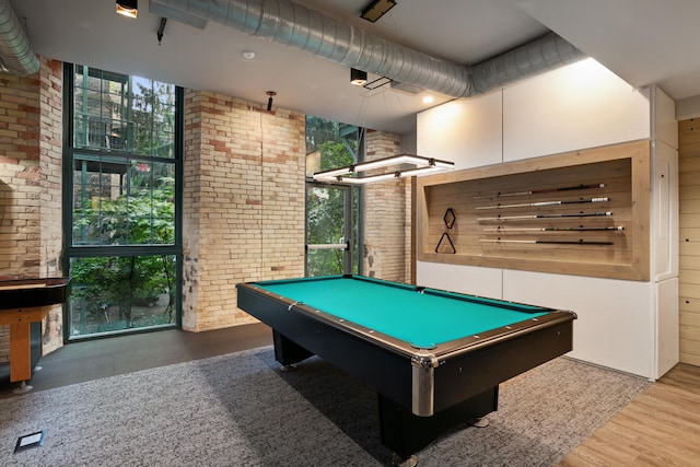 playroom with a wealth of natural light, hardwood / wood-style floors, brick wall, and pool table