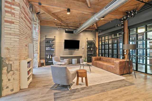 living room featuring beamed ceiling, light hardwood / wood-style floors, a towering ceiling, and wooden ceiling