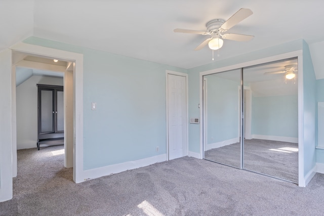 unfurnished bedroom featuring ceiling fan, a closet, light carpet, and vaulted ceiling