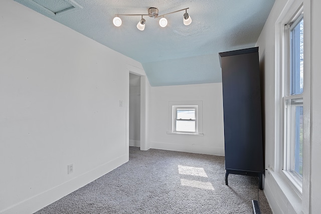 carpeted empty room with a textured ceiling and vaulted ceiling