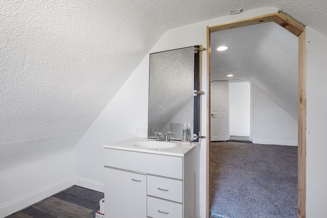 bathroom with lofted ceiling, vanity, a textured ceiling, and hardwood / wood-style flooring