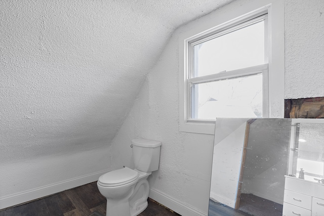 bathroom with vanity, wood-type flooring, vaulted ceiling, and toilet