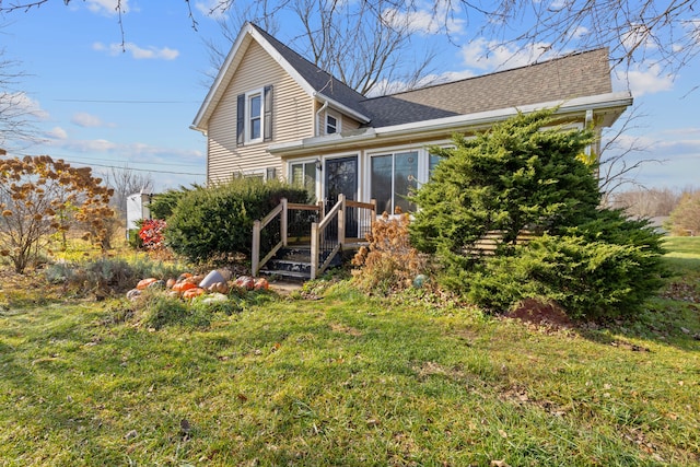 rear view of property with a lawn and a sunroom