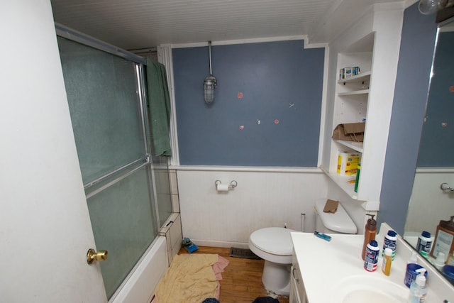 full bathroom featuring hardwood / wood-style flooring, toilet, combined bath / shower with glass door, and vanity