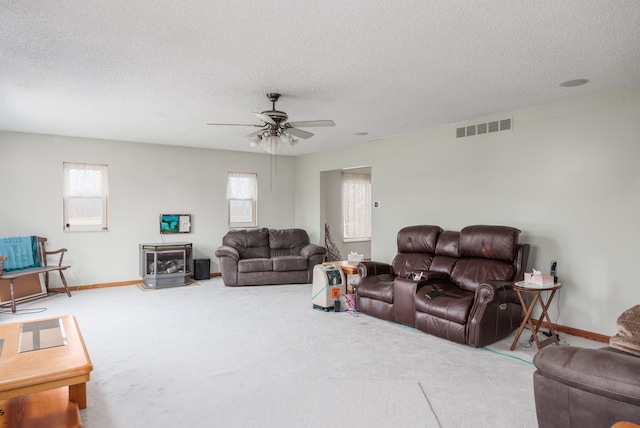 carpeted living room featuring ceiling fan and a textured ceiling