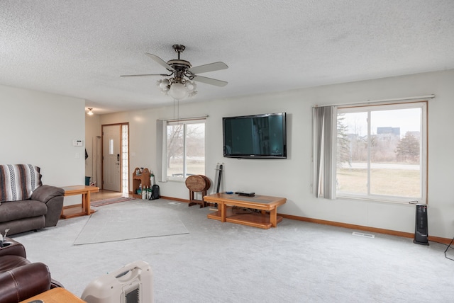 living room with ceiling fan, light colored carpet, and a textured ceiling