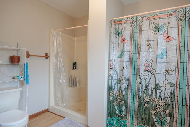 bathroom featuring hardwood / wood-style flooring, toilet, and walk in shower