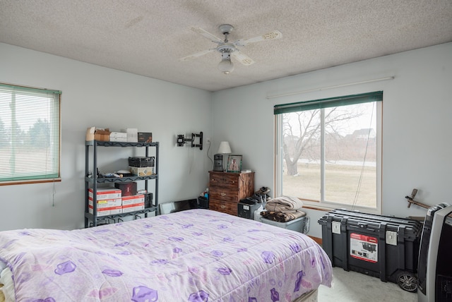 carpeted bedroom featuring ceiling fan and a textured ceiling