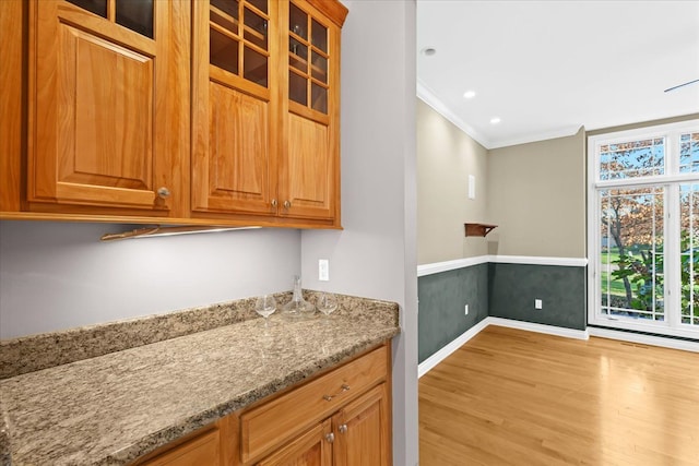 kitchen with light stone countertops, crown molding, and light hardwood / wood-style floors