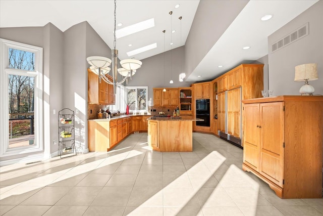 kitchen with high vaulted ceiling, a center island, a wealth of natural light, and a skylight