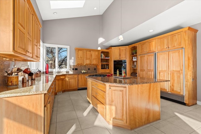 kitchen featuring a skylight, dark stone counters, pendant lighting, light tile patterned floors, and a center island