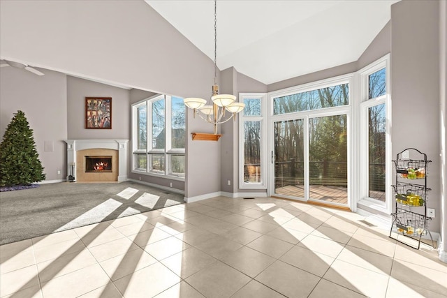 unfurnished dining area with light tile patterned floors, high vaulted ceiling, and a notable chandelier