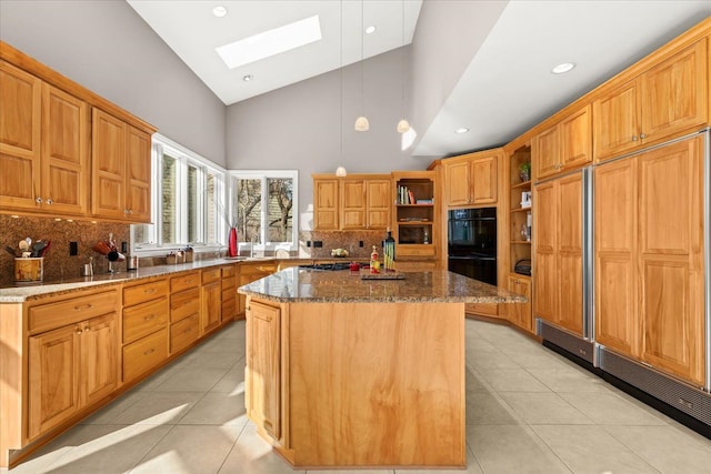 kitchen with a skylight, a center island, high vaulted ceiling, dark stone counters, and light tile patterned floors