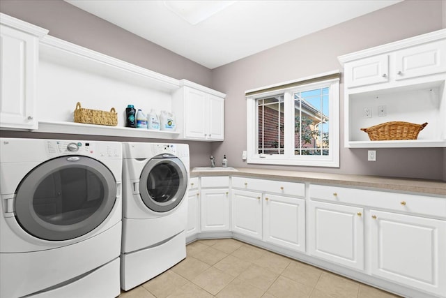 laundry room with washing machine and clothes dryer, sink, light tile patterned floors, and cabinets